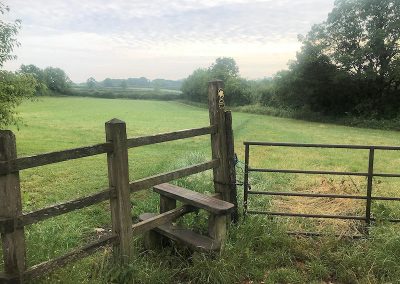 A stile in Mill Street leading to a path along the green fields, by Candida Watson