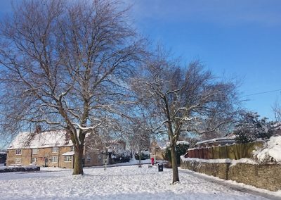 The Old New Inn across the green covered in snow on a clear winter’s day, by Martin Randall